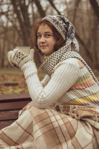 Girl in a funny hat drinking from a mug on the street. - Фото, зображення