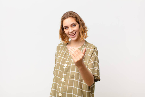 young blonde woman feeling happy, successful and confident, facing a challenge and saying bring it on! or welcoming you against flat color wall - 写真・画像