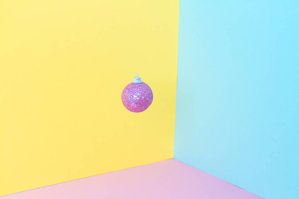 Ροζ παγωμένη χριστουγεννιάτικη μπάλα σε κίτρινο και ροζ φόντο. 3d σύνθεση. Νέο έτος και γενέθλια έννοια. Κενό διάστημα για κείμενο.  - Φωτογραφία, εικόνα