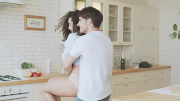 Young couple spinning around in house. Sexy man hugging woman in lingerie. - Video