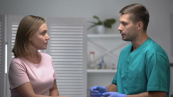Kind male doctor telling about bad diagnosis to upset female patient, medicine - Felvétel, videó