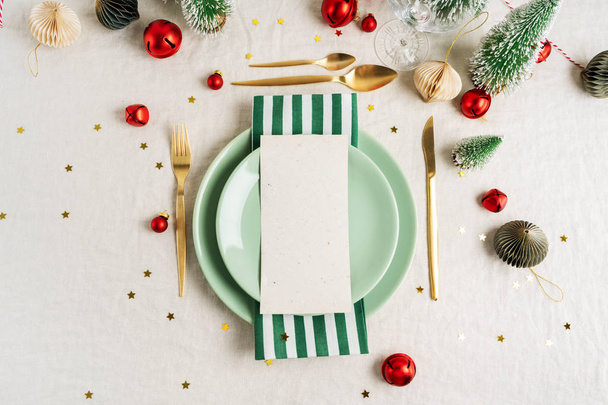 Christmas eve celebration party table setting with plates, golden cutlery, festive vintage decoration, toys over linen tablecloth background. For New Year layout. - Photo, Image