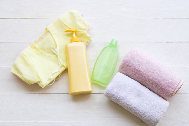 赤ちゃんの綿の服新生児の男の子と女の子はボディローションできれいです,ボディスキンケアのための液体石鹸の健康管理背景にフラットレイスタイル白い木 - 写真・画像