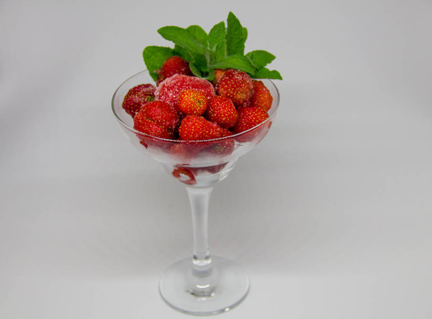 frozen strawberries with mint leaves in a glass on a white background - Photo, image