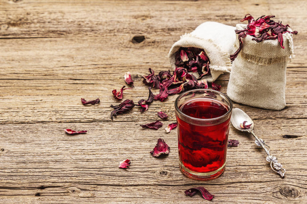 Hot hibiscus tea. Dry petals, linen sacks. Healthy food and self-care concept. Old wooden boards backgrounds - Fotó, kép