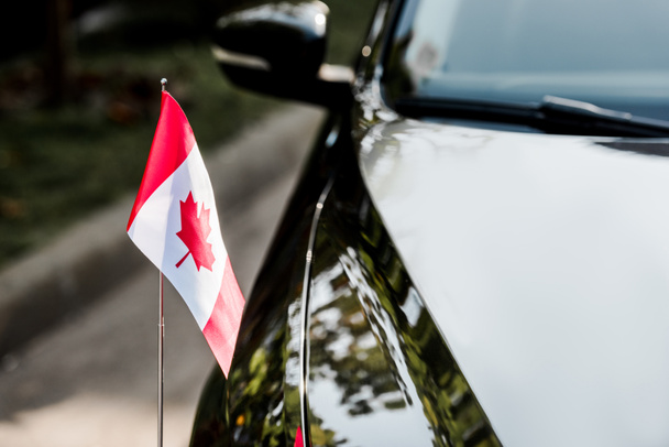 επιλεκτική εστίαση της καναδικής σημαίας με φύλλο σφενδάμου στο μαύρο αυτοκίνητο  - Φωτογραφία, εικόνα