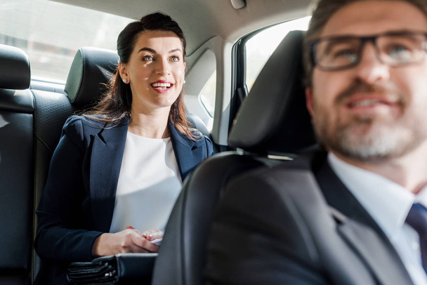 foco seletivo de mulher feliz sentado no carro perto embaixador barbudo
  - Foto, Imagem