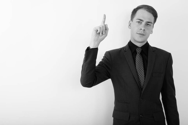 Студийный снимок молодого привлекательного бизнесмена в костюме на белом фоне в черно-белом - Фото, изображение