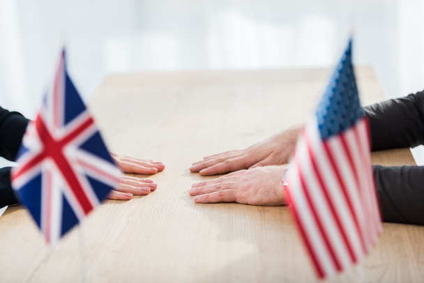 καλλιεργημένη άποψη των διπλωματών κοντά σε σημαίες της Αμερικής και του Ηνωμένου Βασιλείου  - Φωτογραφία, εικόνα
