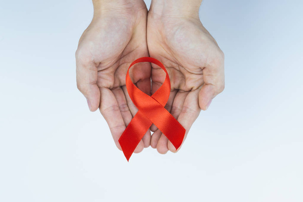 Hilft Bewusstsein, männliche Hände halten rote Aids-Sensibilisierungsschleife  - Foto, Bild