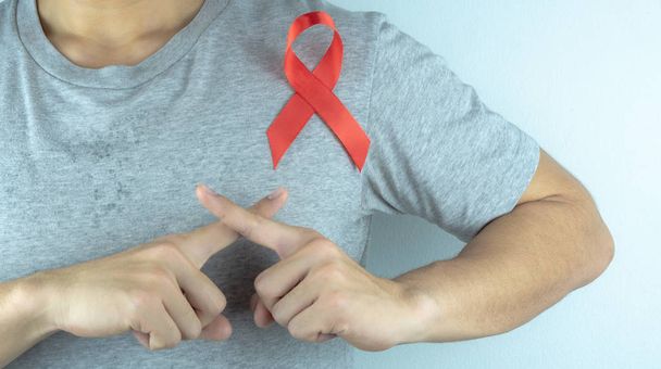 Consciência da SIDA, mãos masculinas segurando fita vermelha da consciência da SIDA. O quê?
 - Foto, Imagem