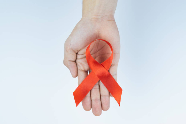 Segédeszközök tudatosítása, vörös AIDS-tudatossági szalagot tartó férfi kezek  - Fotó, kép