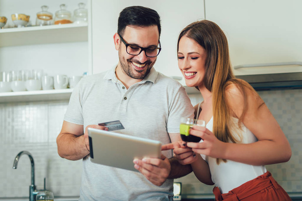 Casal sorridente usando tablet digital e cartão de crédito em casa
 - Foto, Imagem