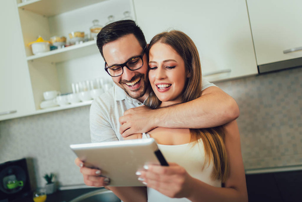 Young couple using digital tablet in the kitchen - Photo, Image