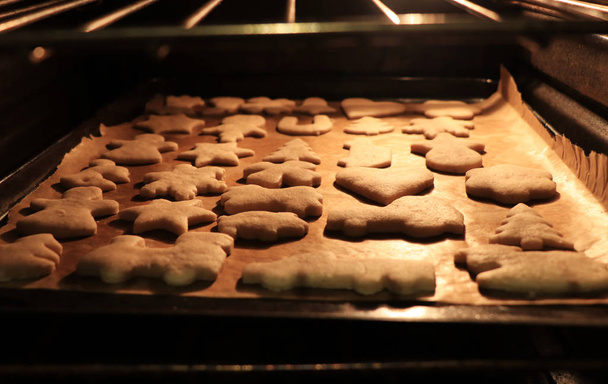 Kerstkoekjes op een bakplaat, in de oven. Warme lichte, weldadige sfeer. Bakken van koekjes. Cadeau voor de Kerstman. Begrip menselijkheid en wintervakantie. Thanksgiving - Foto, afbeelding