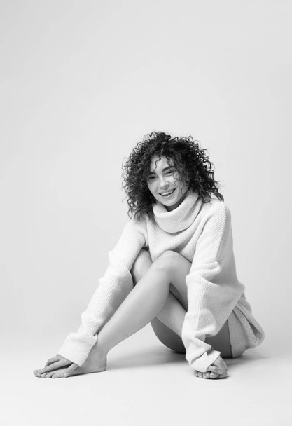 Portrait of lovely woman with curly hair in warm cozy sweater  - 写真・画像