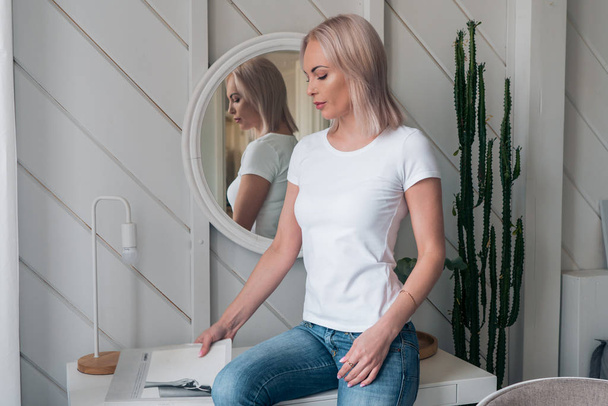 Delicate portrait of a beautiful blonde in a white t-shirt and blue jeans - Fotó, kép