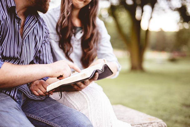 A closeup shot of a couple sitting and reading the bible with a blurred background - Foto, Imagem