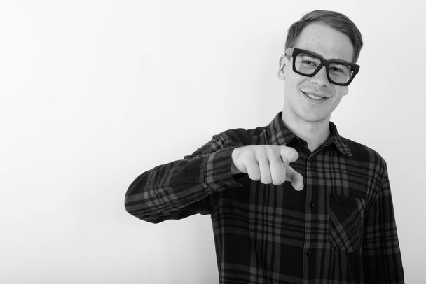 Studio shot of young handsome hipster man wearing eyeglasses against white background in black and white - Foto, Bild