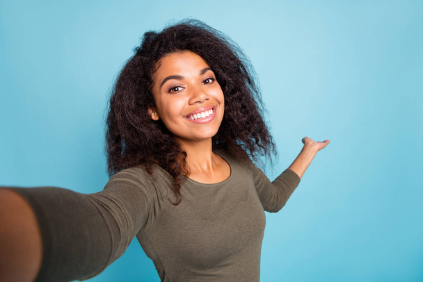Close up photo of positive cheerful afro american tourist girl hold hand invite show her vacation take selfie video call wear casual style shirt isolated over blue color background - Φωτογραφία, εικόνα