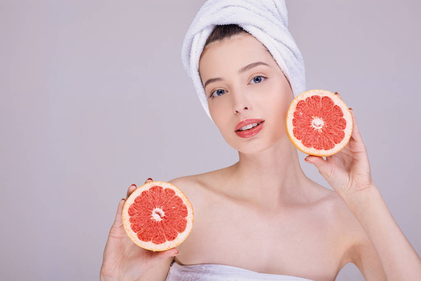 Beauty portrait of a girl with grapefruit near the face. - Valokuva, kuva