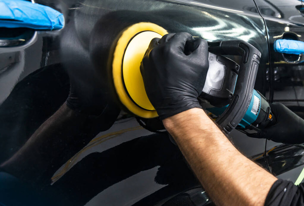 Car polish wax worker hands applying protective tape before polishing. Buffing and polishing car. Car detailing. Man holds a polisher in the hand and polishes the car. Tools for polishing - Foto, Imagen