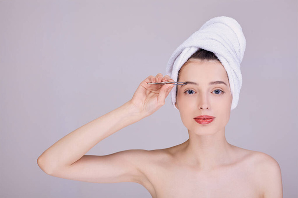 Portrait of a beauty after a shower, plucking eyebrows. - Foto, Bild