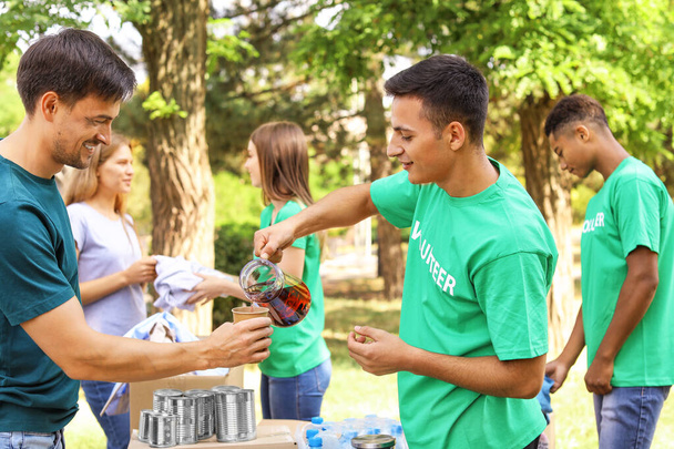 屋外で貧しい人々に食べ物を与える若いボランティア - 写真・画像