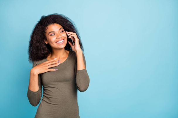 Portrait of positive cheerful mulatto girl have conversation with her friend using cellphone listen news enjoy break pause wear casual style clothes isolated over blue color background - 写真・画像
