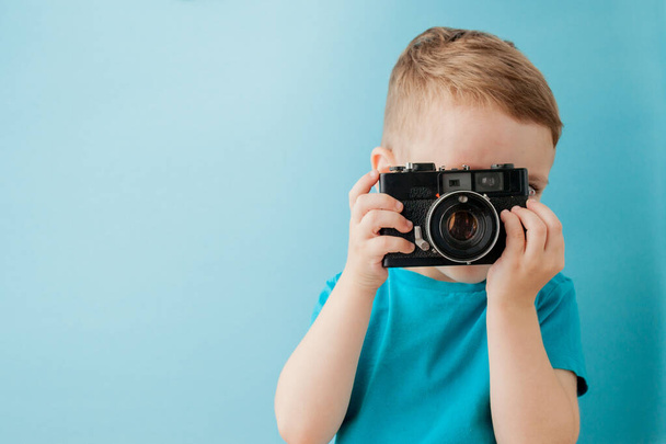 Little boy with an old camera on a blue background - Zdjęcie, obraz