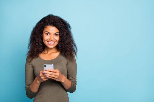Portrait of cheerful positive sweet mulatto girl use her smartphone type text post comments in blog social network account wear casual style clothes isolated over blue color background - Fotografie, Obrázek
