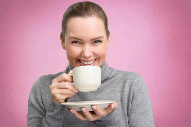 Νεαρή γυναίκα απολαμβάνει ένα φλιτζάνι καφέ ή τσάι - Φωτογραφία, εικόνα