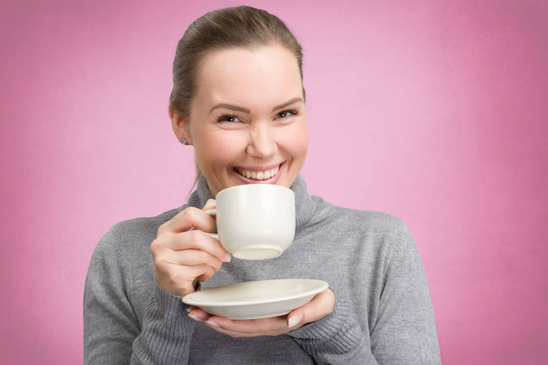 Νεαρή γυναίκα απολαμβάνει ένα φλιτζάνι καφέ ή τσάι - Φωτογραφία, εικόνα