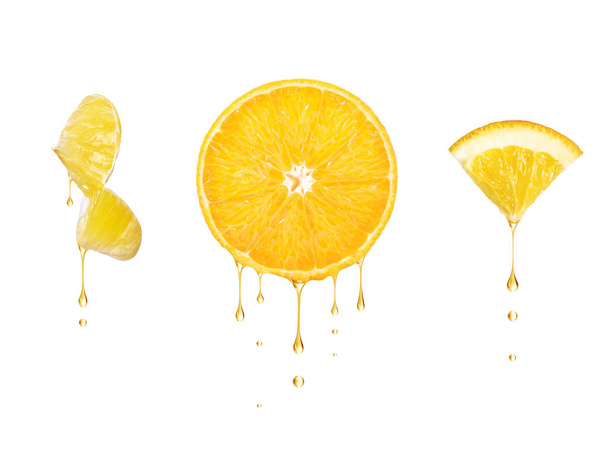 Drops of juice drip from cut pieces of orange, isolated on white background - Photo, image