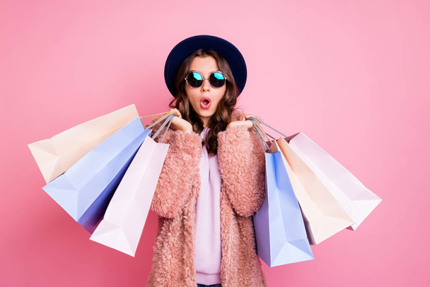 Photo of pretty millennial lady carry many packs shopper tourism abroad look unbelievable sales low prices mall wear fluffy jacket sun specs blue hat isolated pink background - Foto, immagini