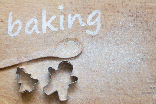 Christmas background with cookies molds and spoon. Baking text made with flour - Valokuva, kuva