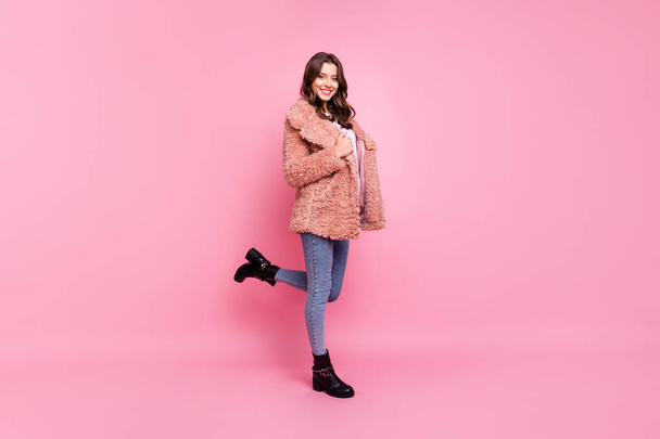 Full length profile photo of amazing millennial model lady standing confidently wearing stylish youth fluffy autumn jacket jeans shoes isolated pink background - Фото, изображение