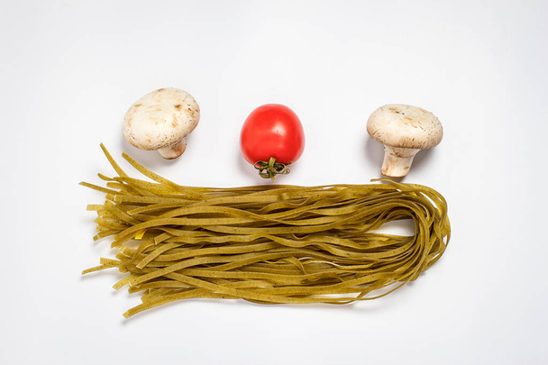 Raw pasta, fresh vegetables, tomatoes and mushrooms on a white plate close - Foto, immagini