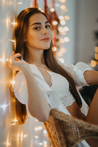Fiatal nő ül a karosszékben, és mosolyog a karácsonyfa - Fotó, kép