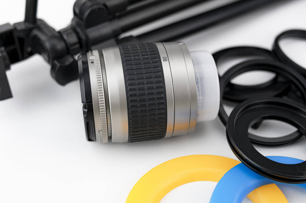 Photo camera lens close-up, with lens protectors and small tripod on white background - Photo, Image