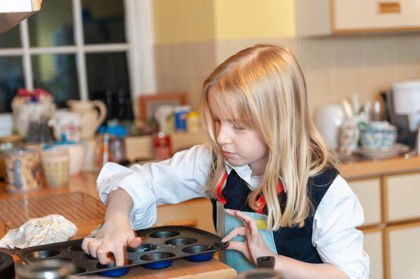 hübsche junge blonde Mädchen bereitet sich auf Backen in einer chaotischen Küche - Foto, Bild