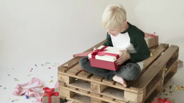 Boy blond opens a box with a gift.  - Imágenes, Vídeo