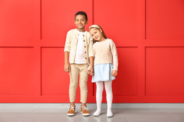 Niños pequeños de moda en ropa de otoño cerca de la pared de color
 - Foto, imagen