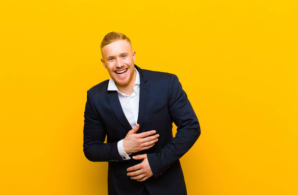 young blond businessman laughing out loud at some hilarious joke, feeling happy and cheerful, having fun - Photo, image