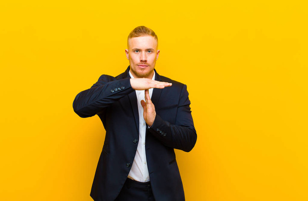 young blond businessman looking serious, stern, angry and displeased, making time out sign - Foto, Bild
