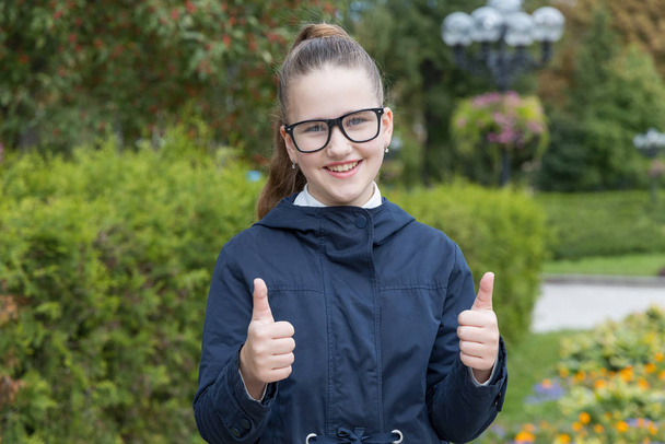 Happy teenager girl showing thumbs up. Schoolgirl with glasses. - Foto, Imagen