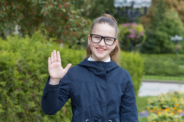 Hello! Happy teenager girl waving. Schoolgirl with glasses. - Zdjęcie, obraz