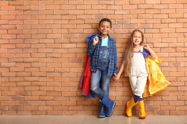 Модні маленькі діти в осінньому одязі біля цегляної стіни
 - Фото, зображення