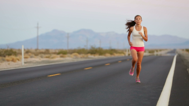 žena běžec běží na otevřené silnici v krajině - Záběry, video
