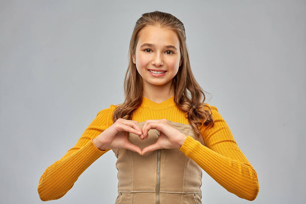 smiling teenage girl making hand heart - Foto, Imagem